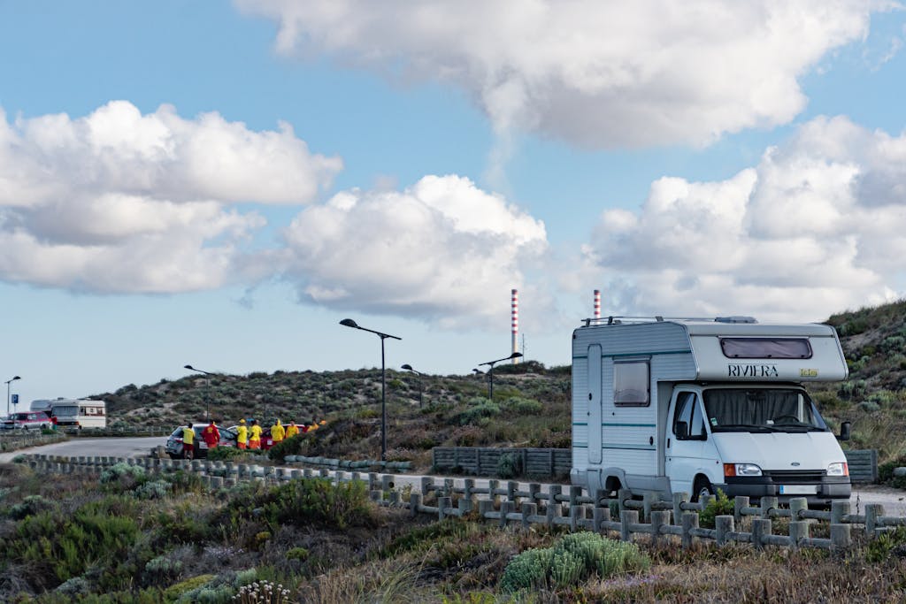Campervan parked in Portugal's scenic landscape under a bright blue sky with fluffy clouds. if you're planning to drive a motorhome in Portugal