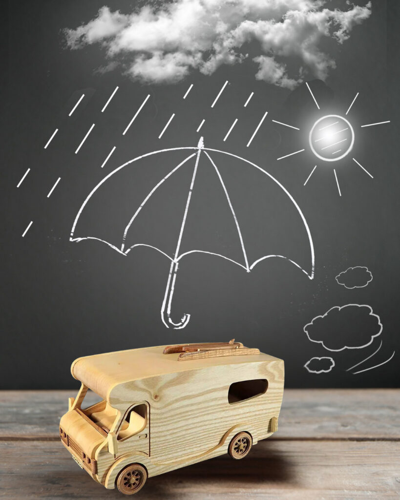 Chalkboard wall with umbrella, sun, and rain illustrations behind a wooden camper van toy, ideal for travel inspiration and adventure decor.